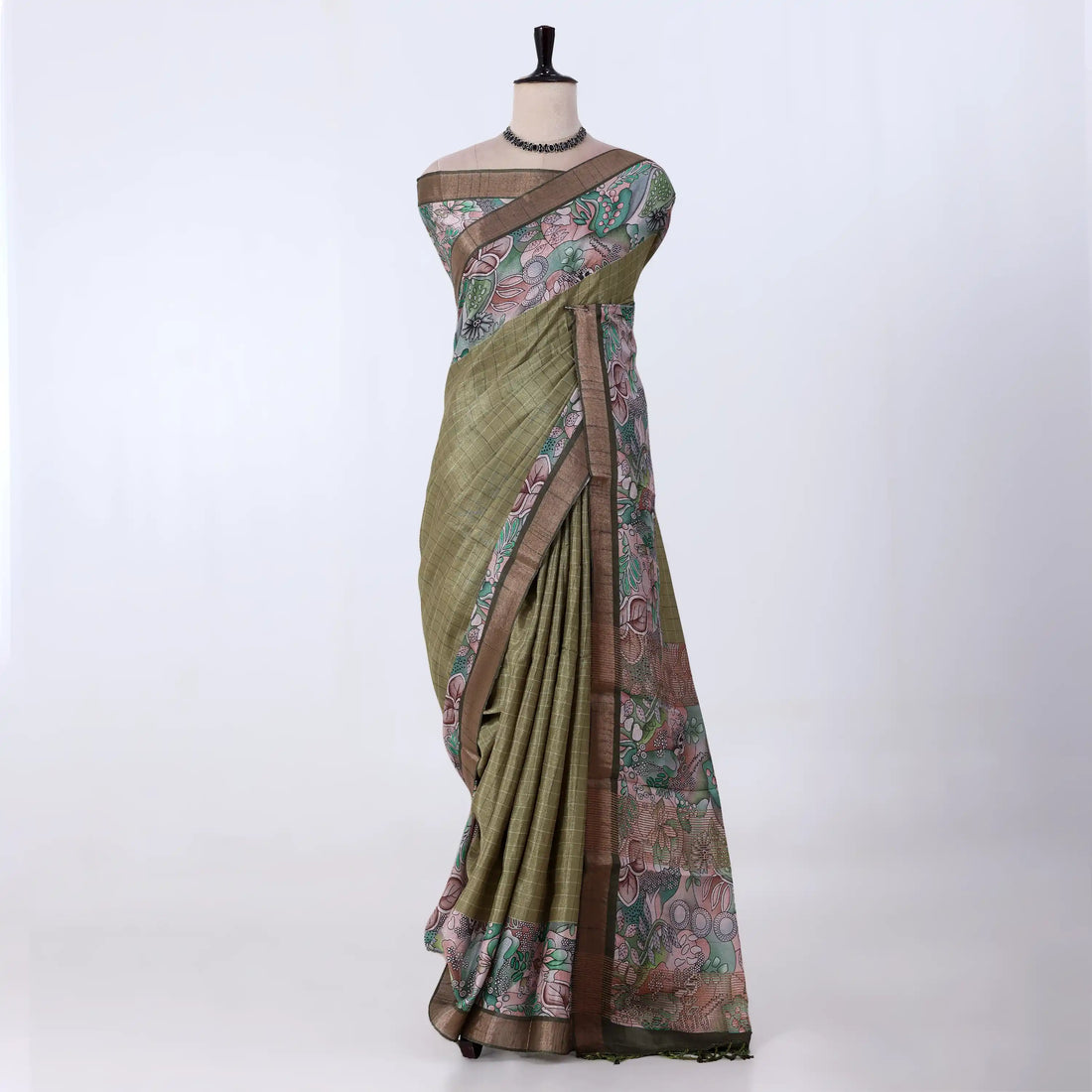 A green and brown printed saree features a sage green body with brown borders and pink floral patterns.