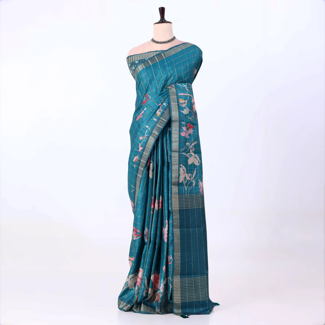 A teal blue saree with a subtle grid pattern and pink floral prints