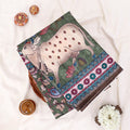 A folded patterned saree featuring a ptinted cow motif, floral elements, and a decorative border. 