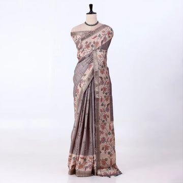 A traditional tusser saree with taupe-gray base with a floral block-print pattern in muted pink, green, and brown tones.