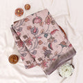 A folded light pink saree with a detailed multicolor floral and bird pattern