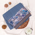 A folded blue and brown printed saree features a sage blue body with brown borders