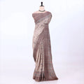 The saree has a warm taupe and brown base with a subtle plaid pattern and ornate multicolor border details in blue, red, and green.