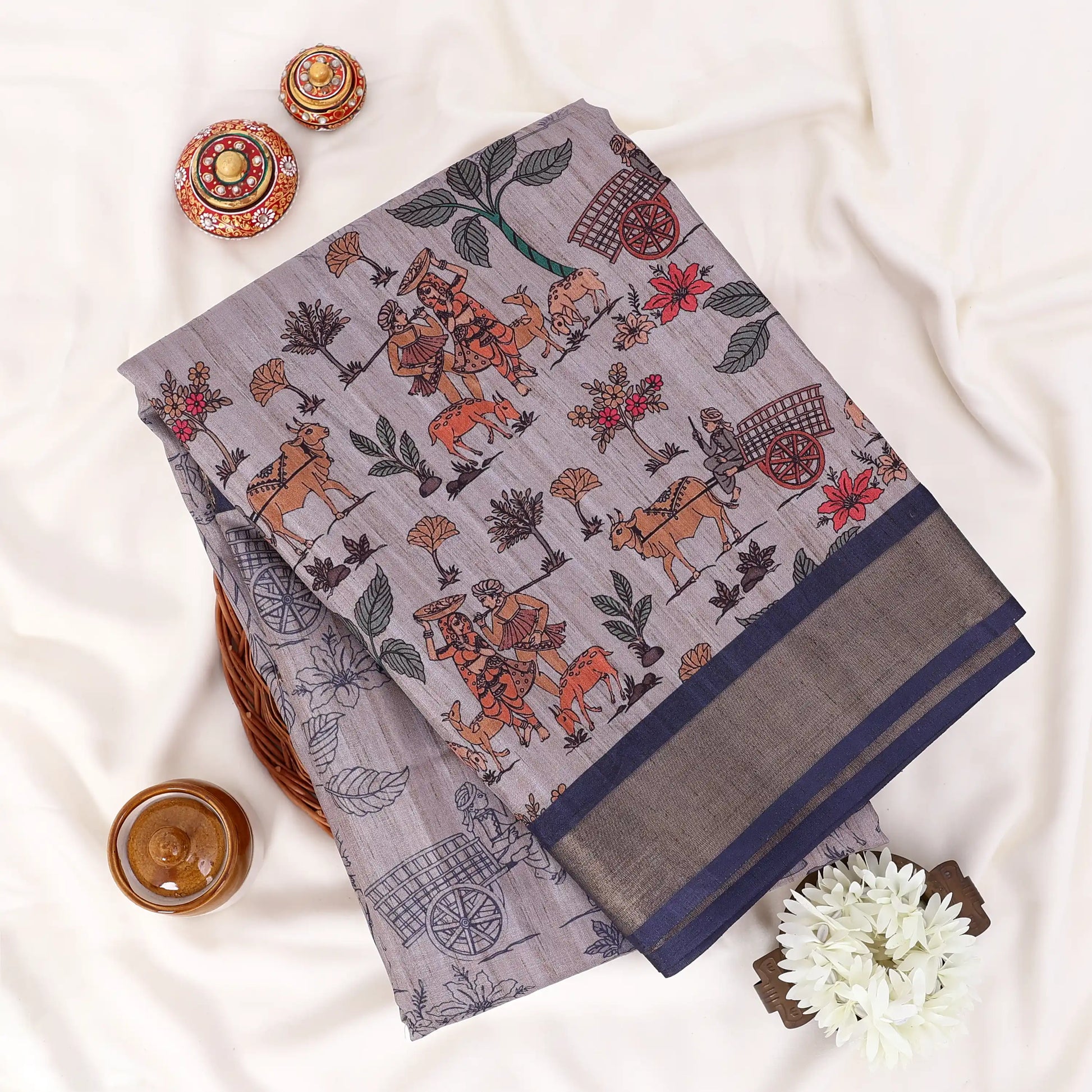 light grey Semi Tussar saree featuring floral print and navy woven border, folded display.