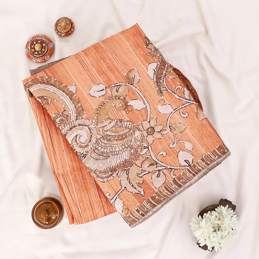 An orange saree with intricate silver and gold floral embroidery