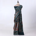 A dark teal saree with intricate multicolor traditional patterns and borders