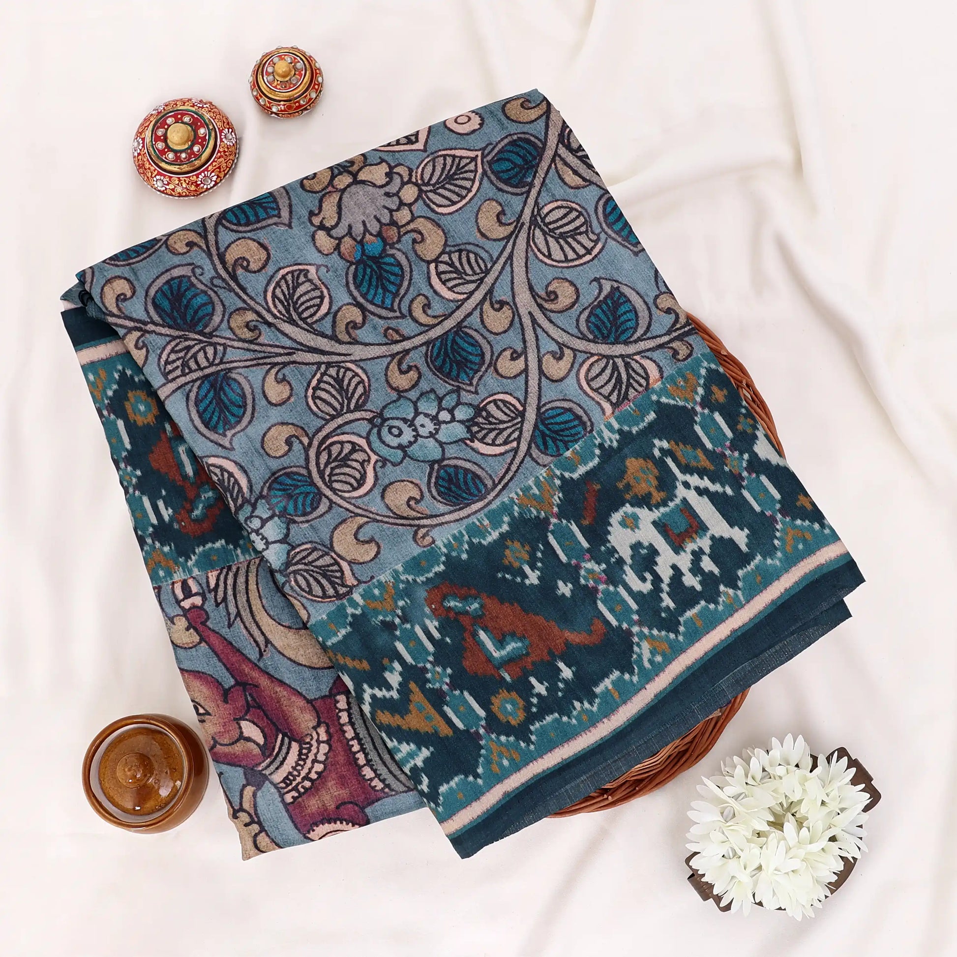 A Folded dark teal saree with intricate multicolor traditional patterns and borders