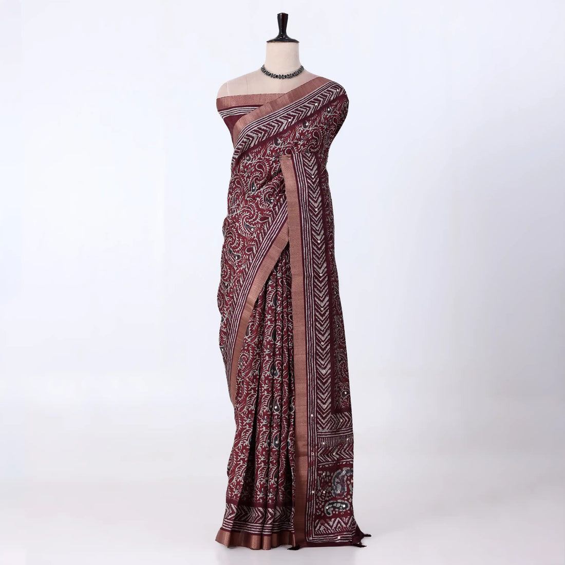 A dark maroon  and gray patterned saree with traditional block prints and a metallic gray border