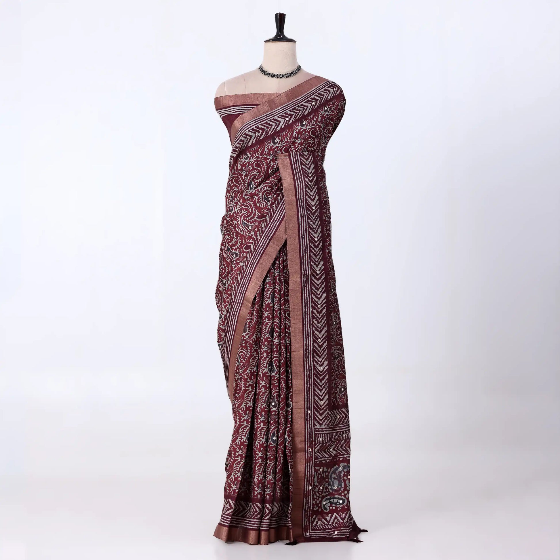 A dark maroon  and gray patterned saree with traditional block prints and a metallic gray border