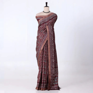 A dark maroon  and gray patterned saree with traditional block prints and a metallic gray border