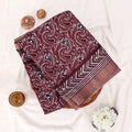 A folded piece of maroon paisley printed fabric with a striped border