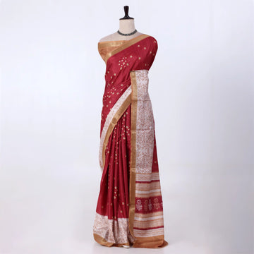 A deep red silk saree with gold zari embroidery and a beige-and-red patterned border