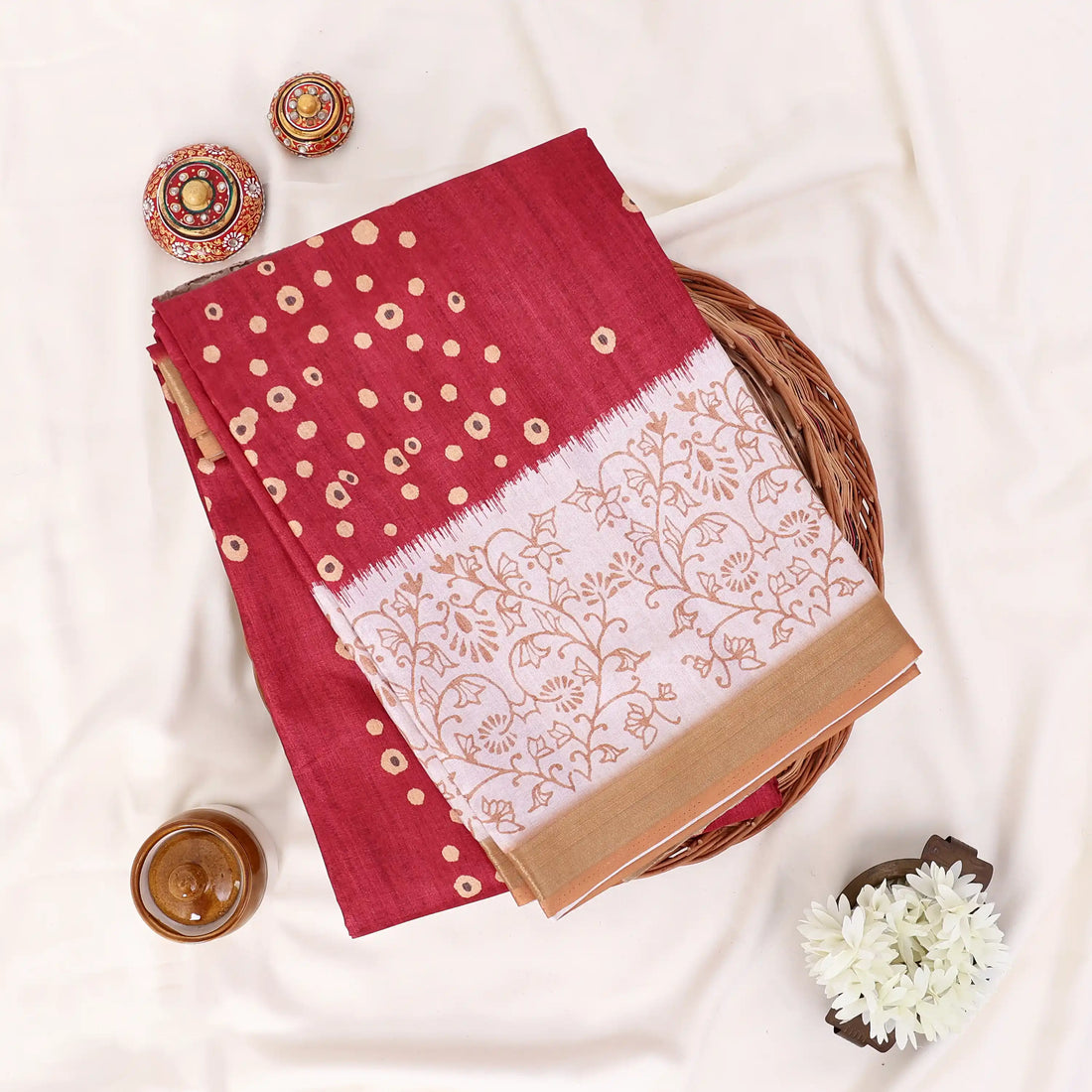 A deep red silk saree with gold zari embroidery and a beige-and-red patterned border