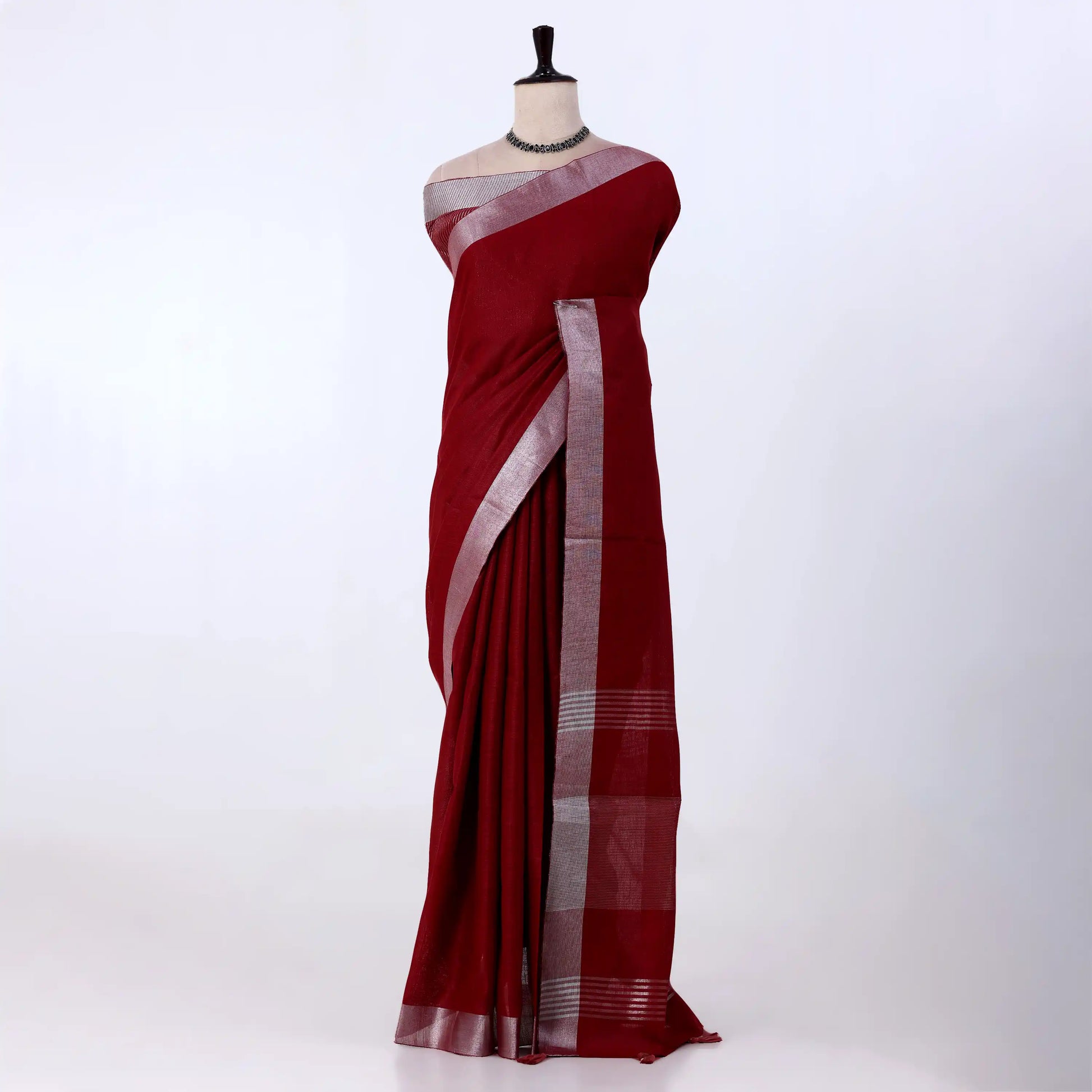A deep red cotton saree with a silver metallic border