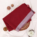 A folded deep red saree with a light purple border
