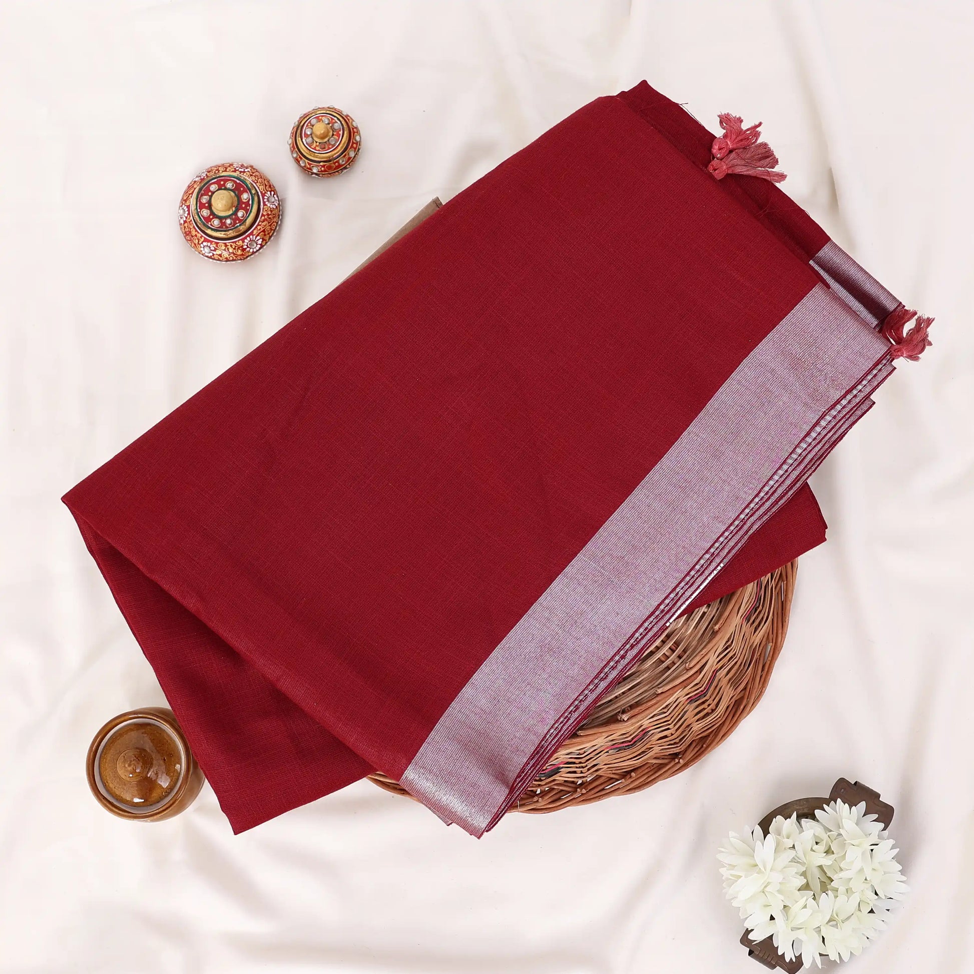 A folded deep red saree with a light purple border