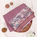 A folded mauve and pink patterned saree with features a solid mauve border, a floral printed pallu, and a matching printed blouse piece.