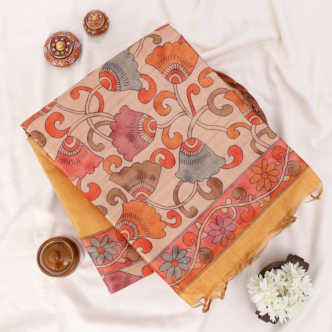 A golden yellow saree featuring a wide beige border and a patterned pallu with red, green, and gold motifs