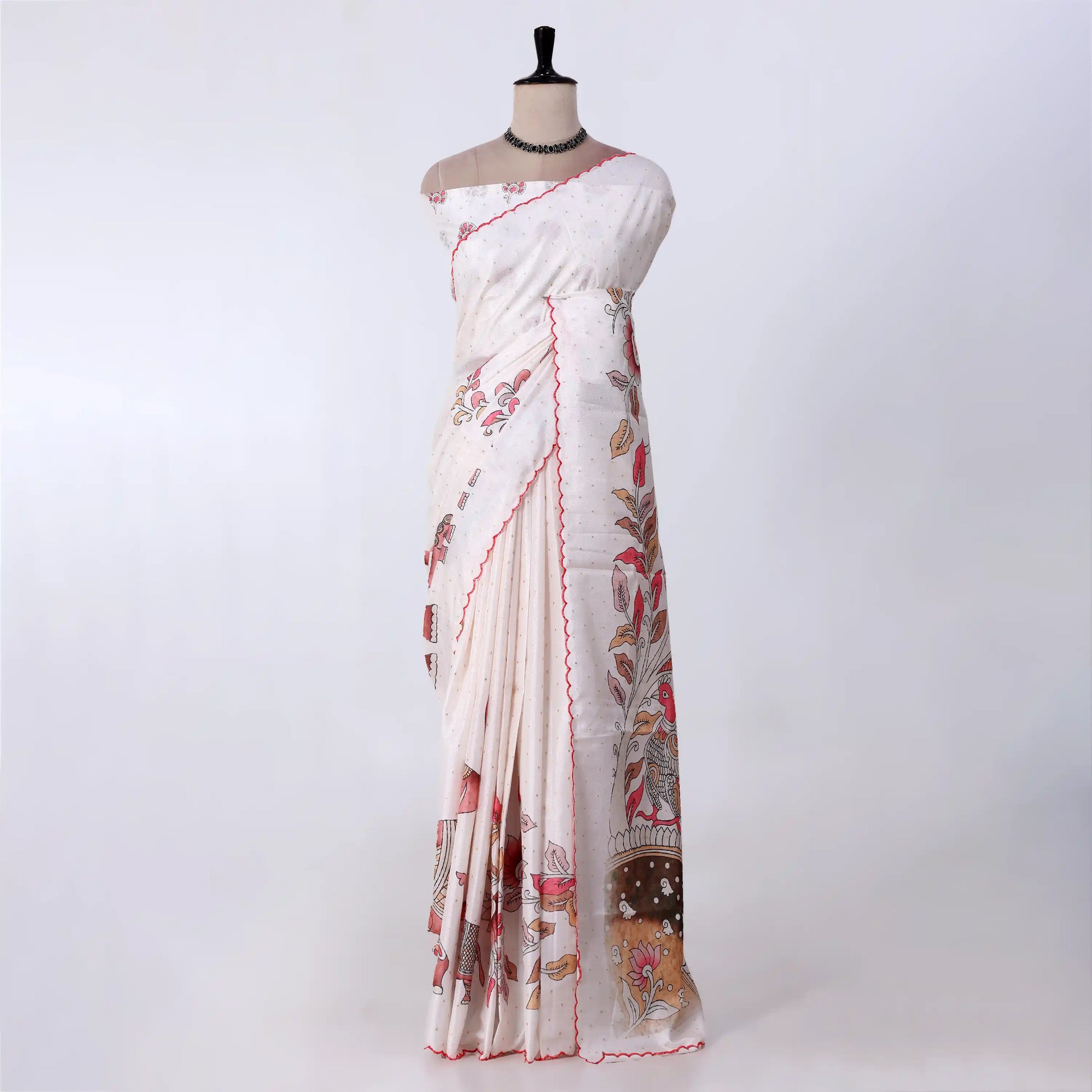 A white and beige printed saree with red border trim and floral motifs