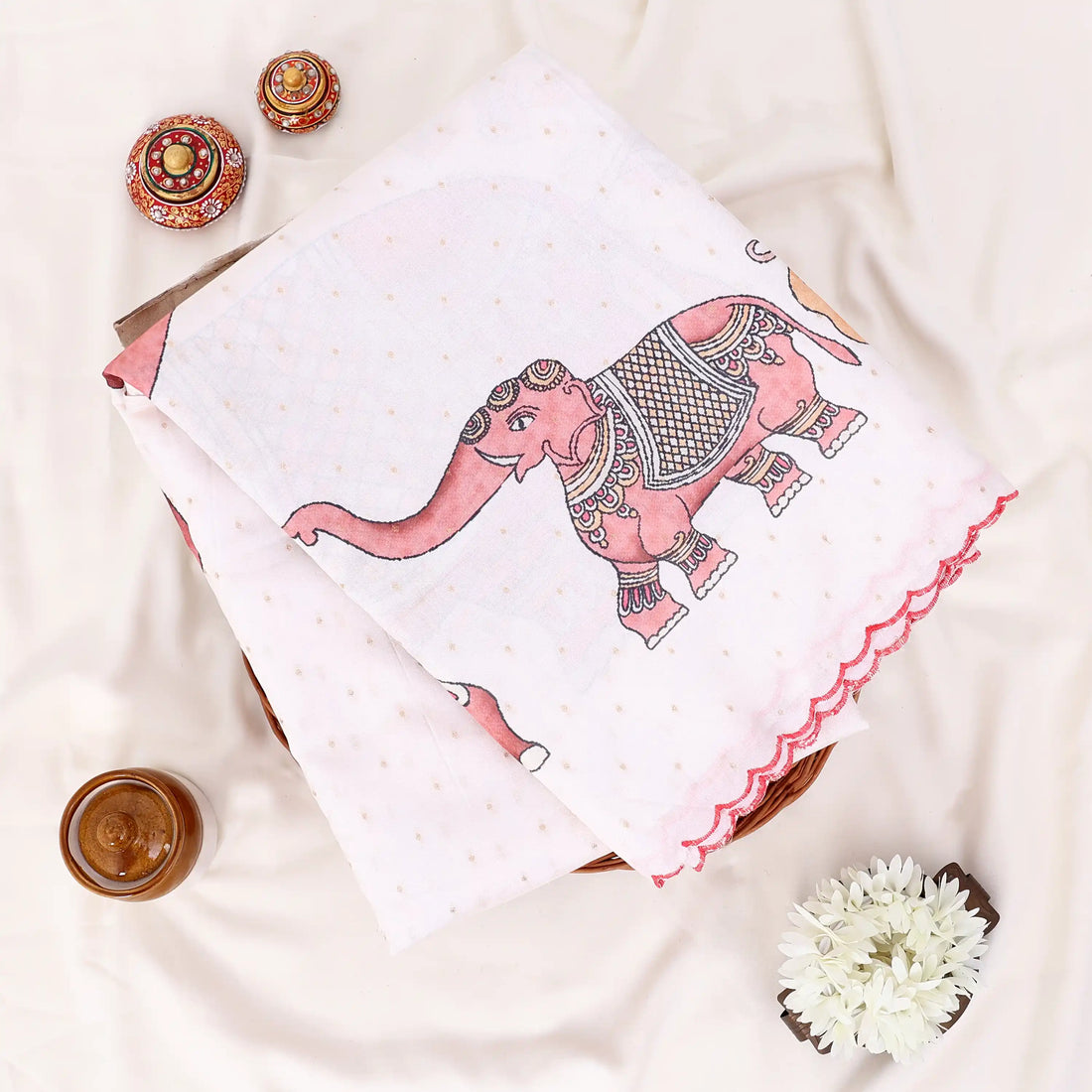 A white and beige printed saree with red border trim and floral motifs