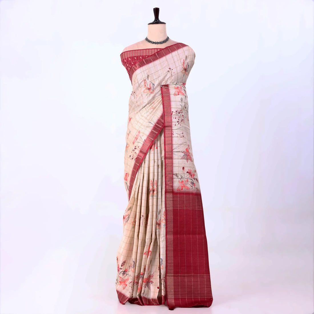 A beige and red saree with floral patterns and a red border