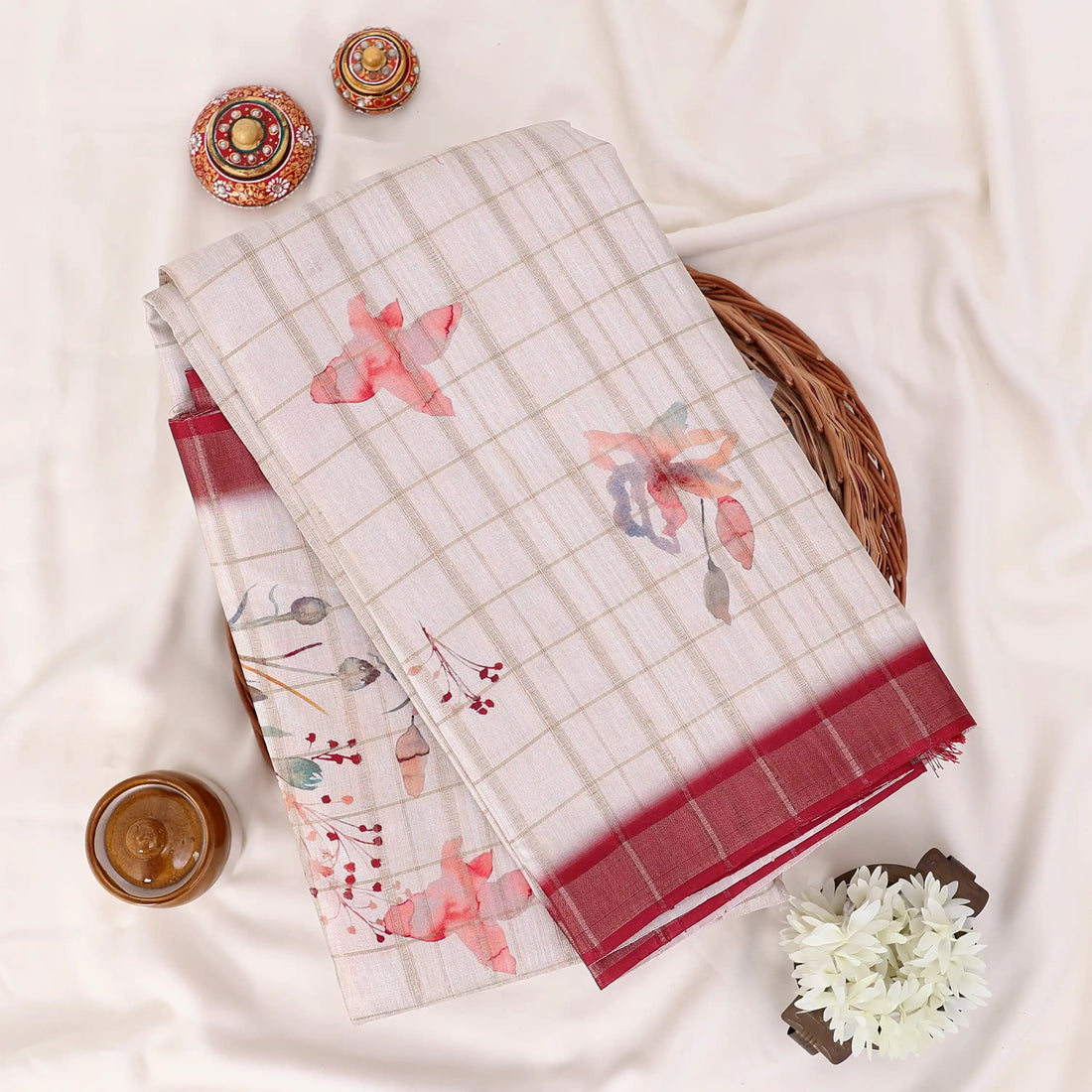 A beige and red saree with floral patterns and a red border