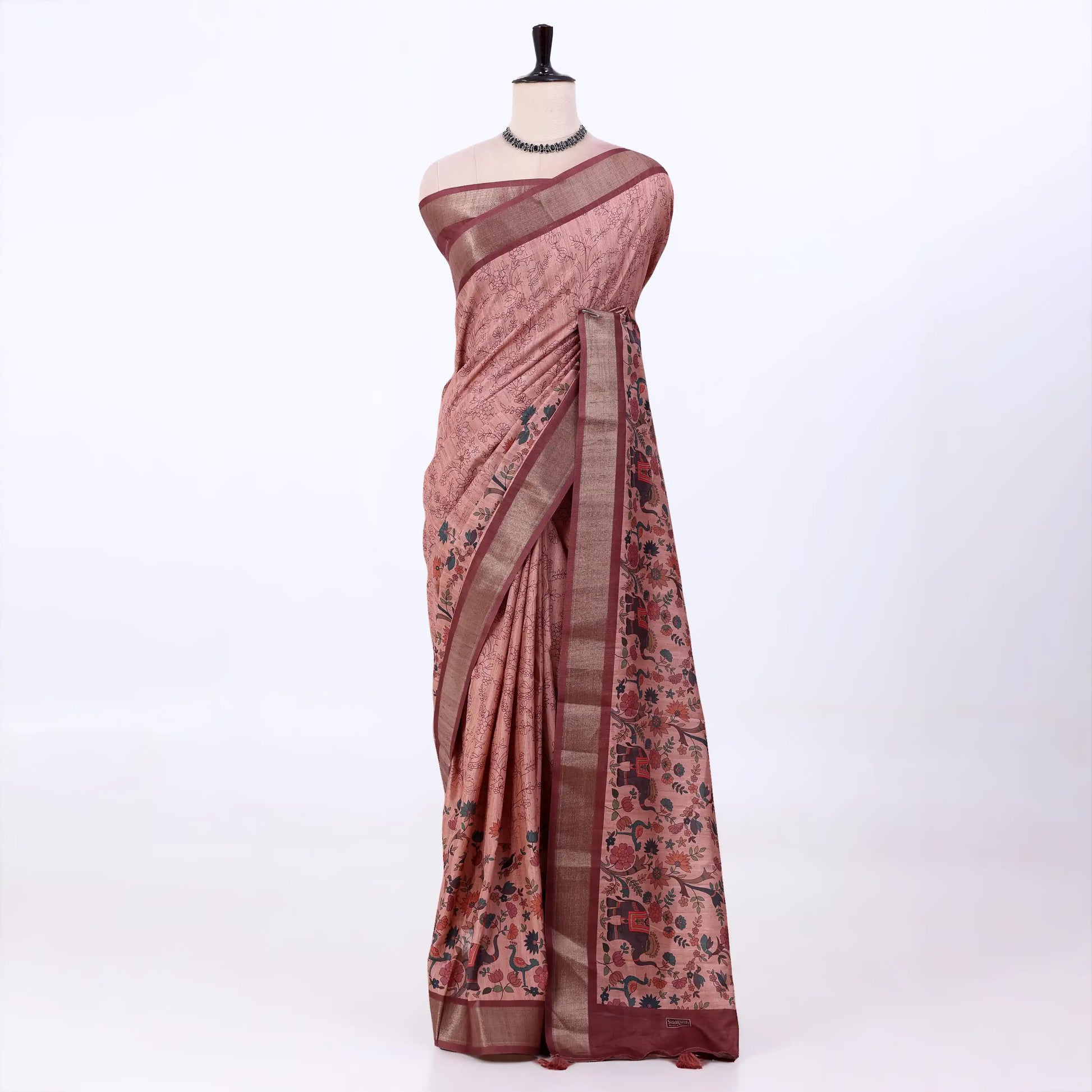 A dusty rose pink tusser saree with black floral motifs and a brown border, draped 