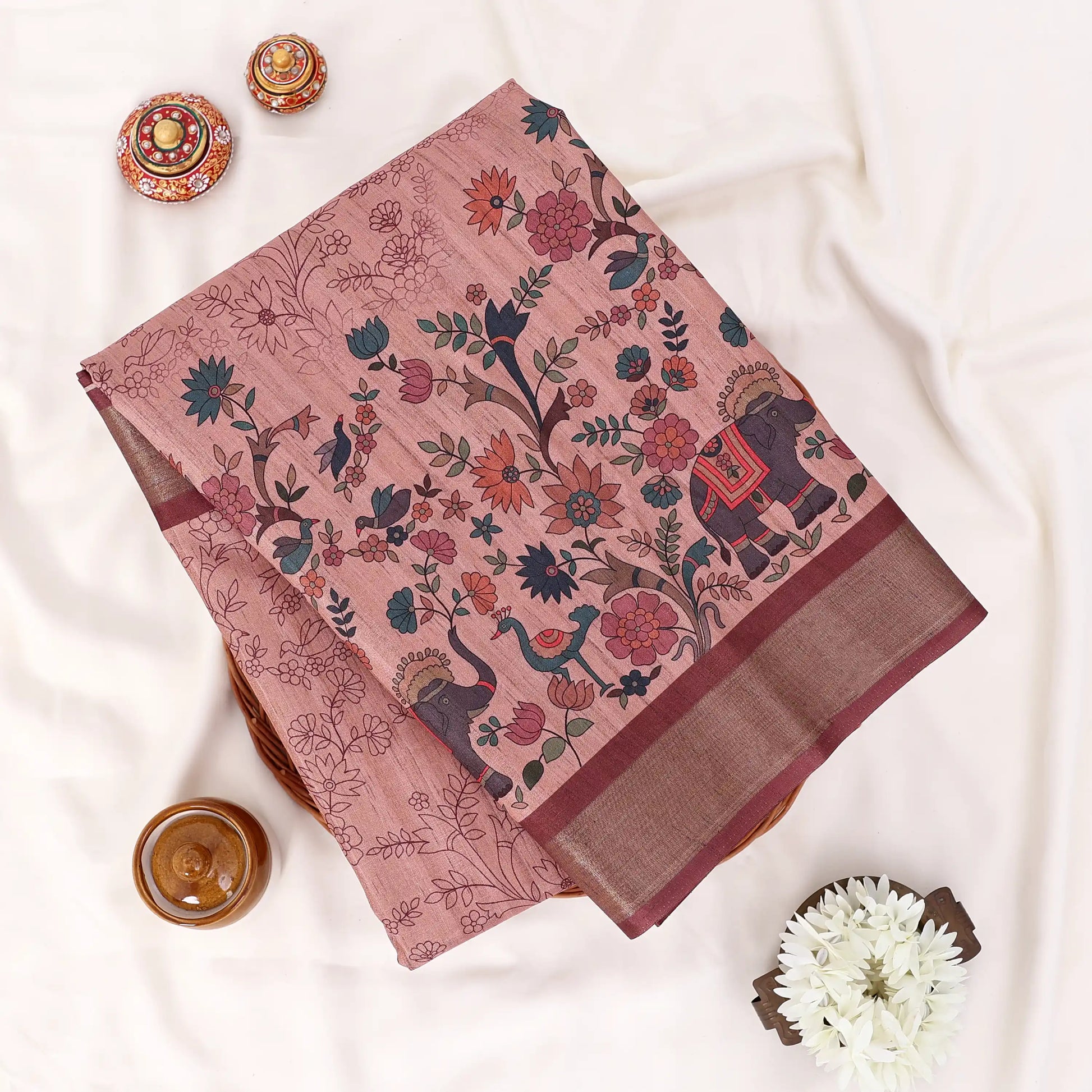 A flat-lay photograph of a dusty pink cotton saree with traditional Indian block prints