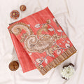 A folded coral-red saree with a large beige and gold paisley and floral motif
