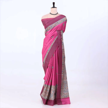 A magenta pink silk saree with a detailed multicolor border