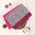 A folded pink and magenta fabric piece with a detailed multicolor printed border featuring floral and figure motifs