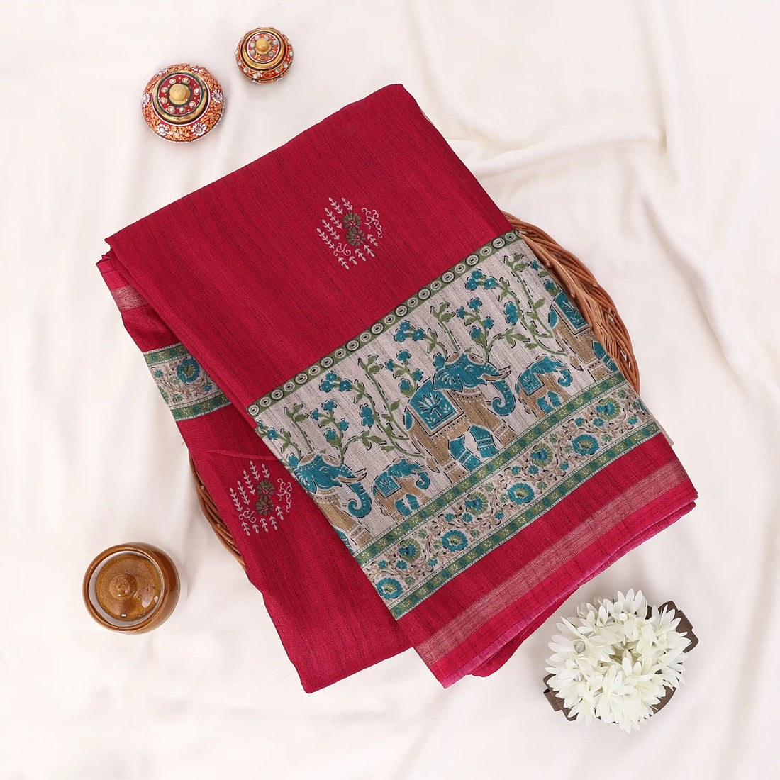 A red cotton saree with green and gold border patterns