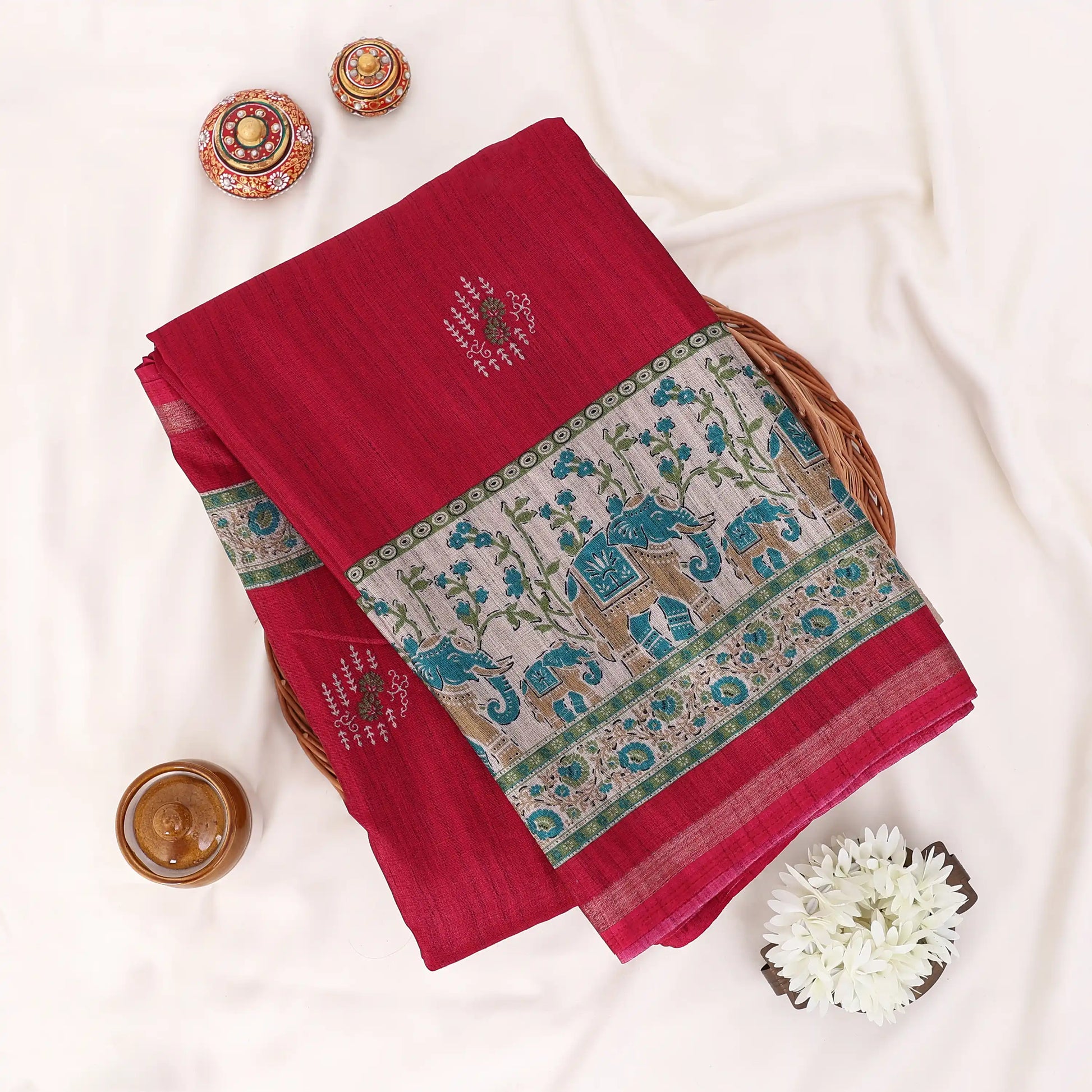 A red cotton saree with green and gold border patterns