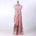 A pink saree with a subtle grid pattern and a floral print in muted blue, brown, and green