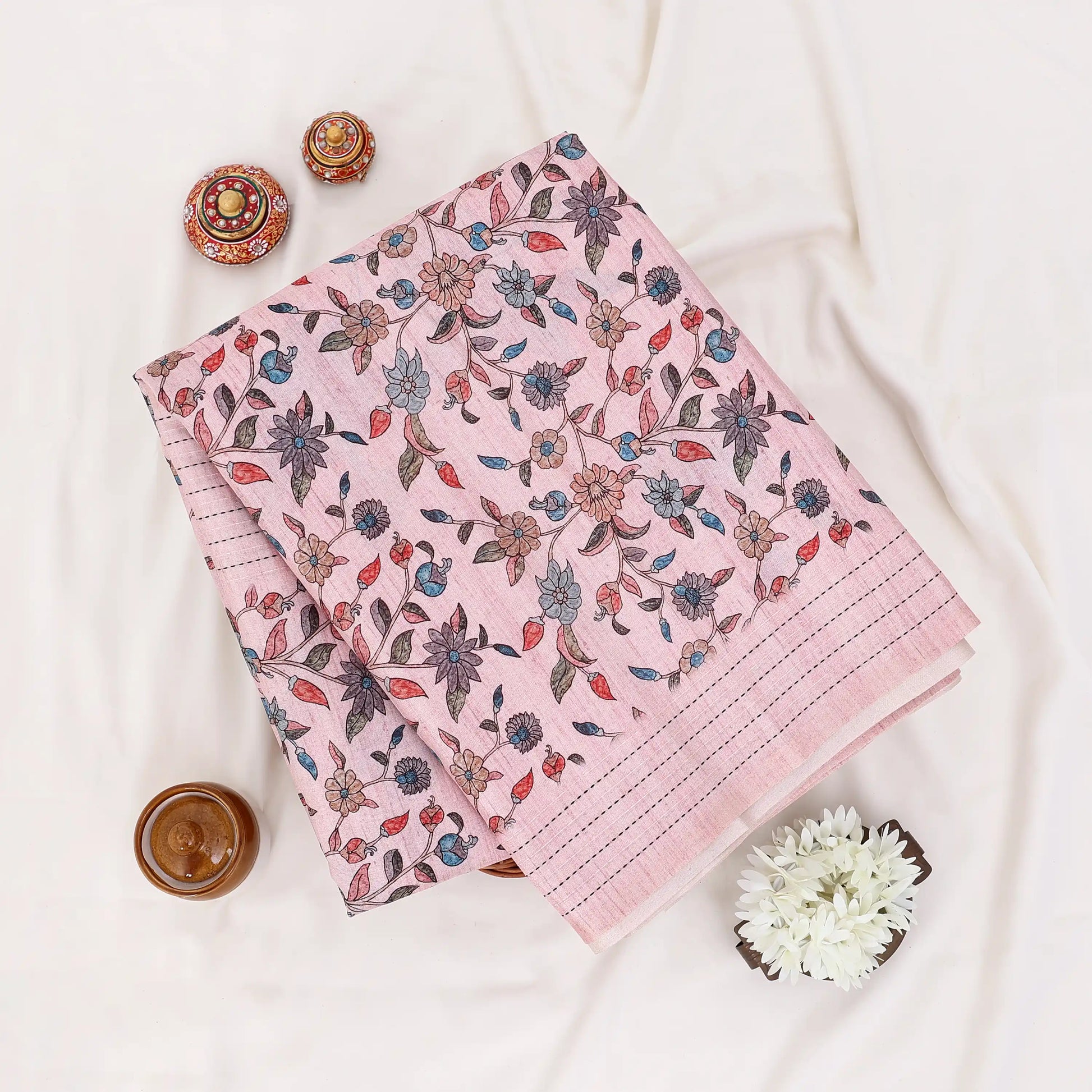 A folded pink fabric piece with a multicolor floral and leaf print