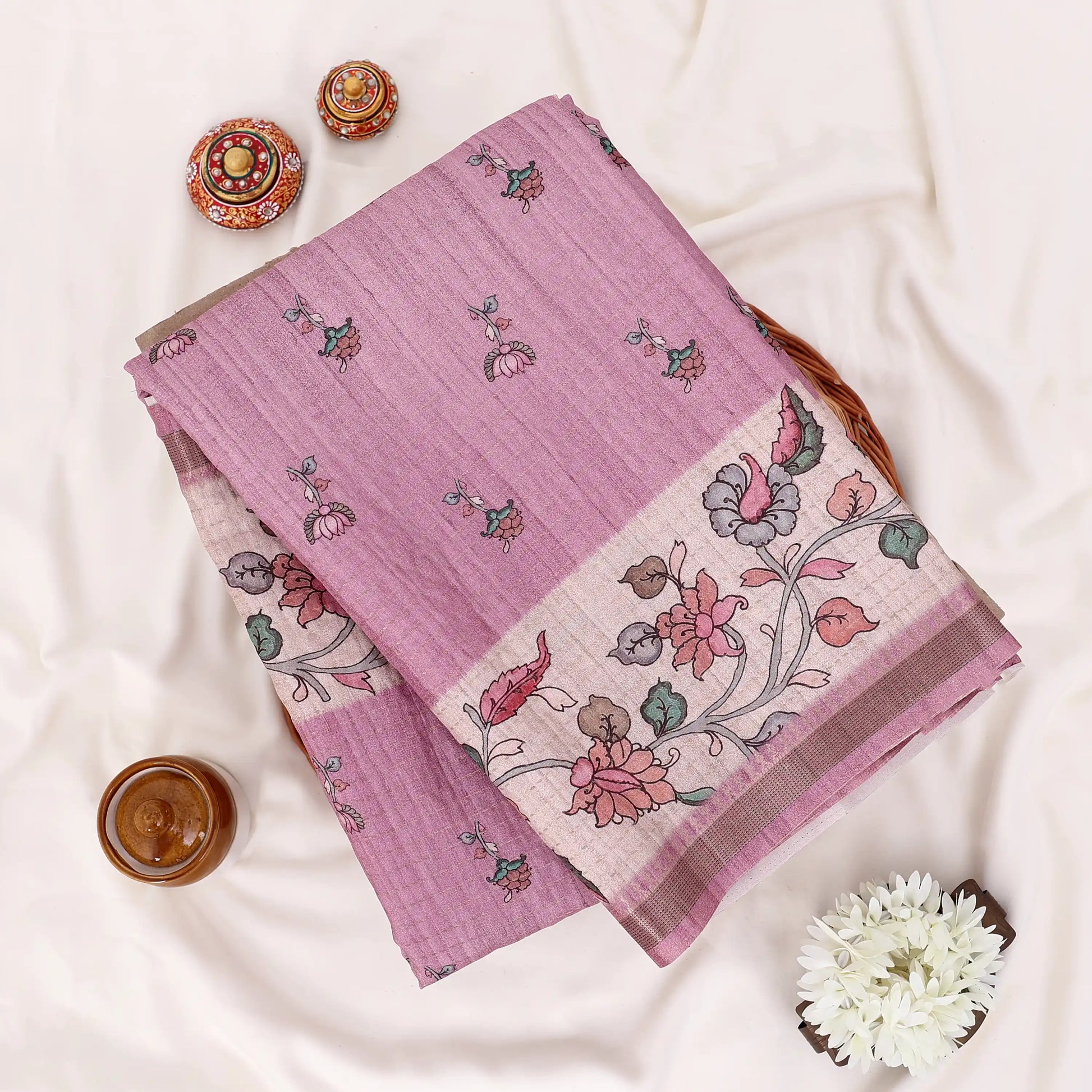 A folded pink and beige floral printed saree with matching border