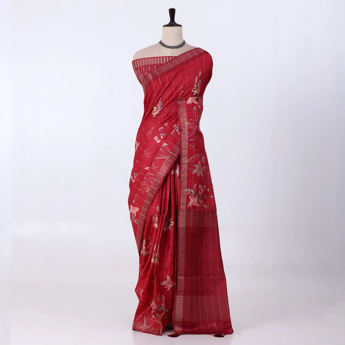 A red tussar saree with white floral prints and a striped border