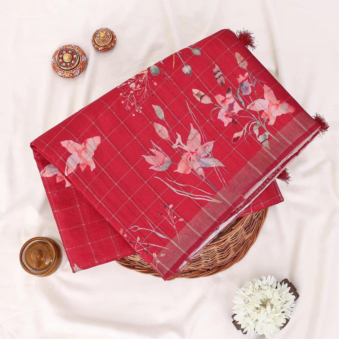 A red tussar saree with white floral prints and a striped border