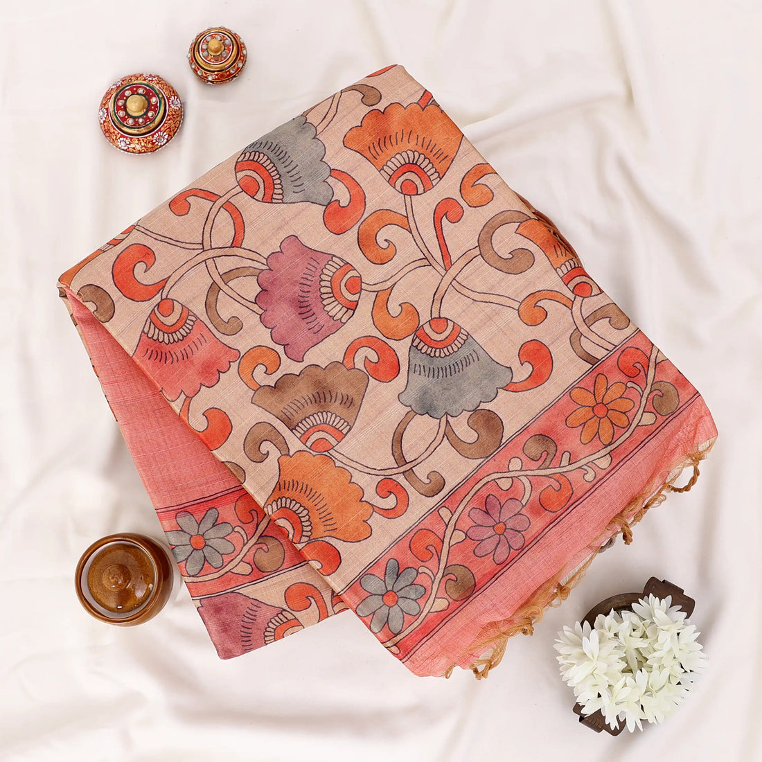 A peach-colored ilk saree with a beige border and a patterned orange and gold pallu