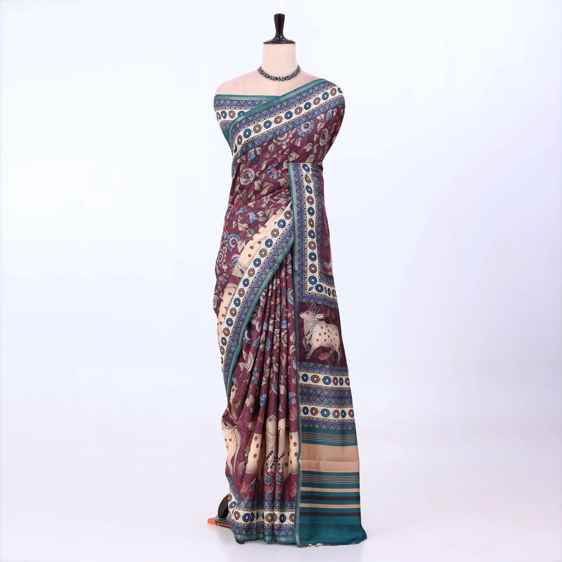 A multicolor printed saree features a deep maroon base with cream, teal, and gold patterns, including traditional motifs and striped borders.