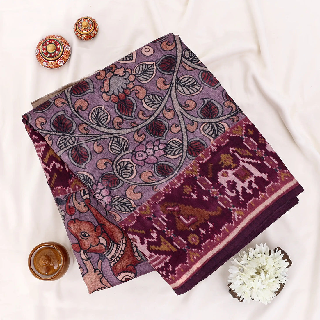 A dark plum purple saree with intricate red and gold floral patterns