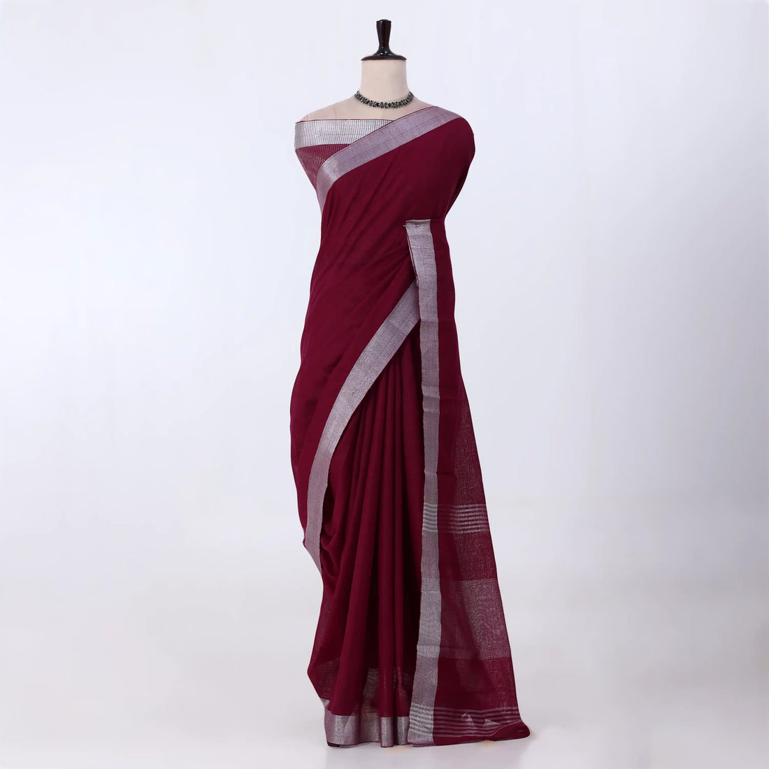 A deep maroon red saree with a silver border