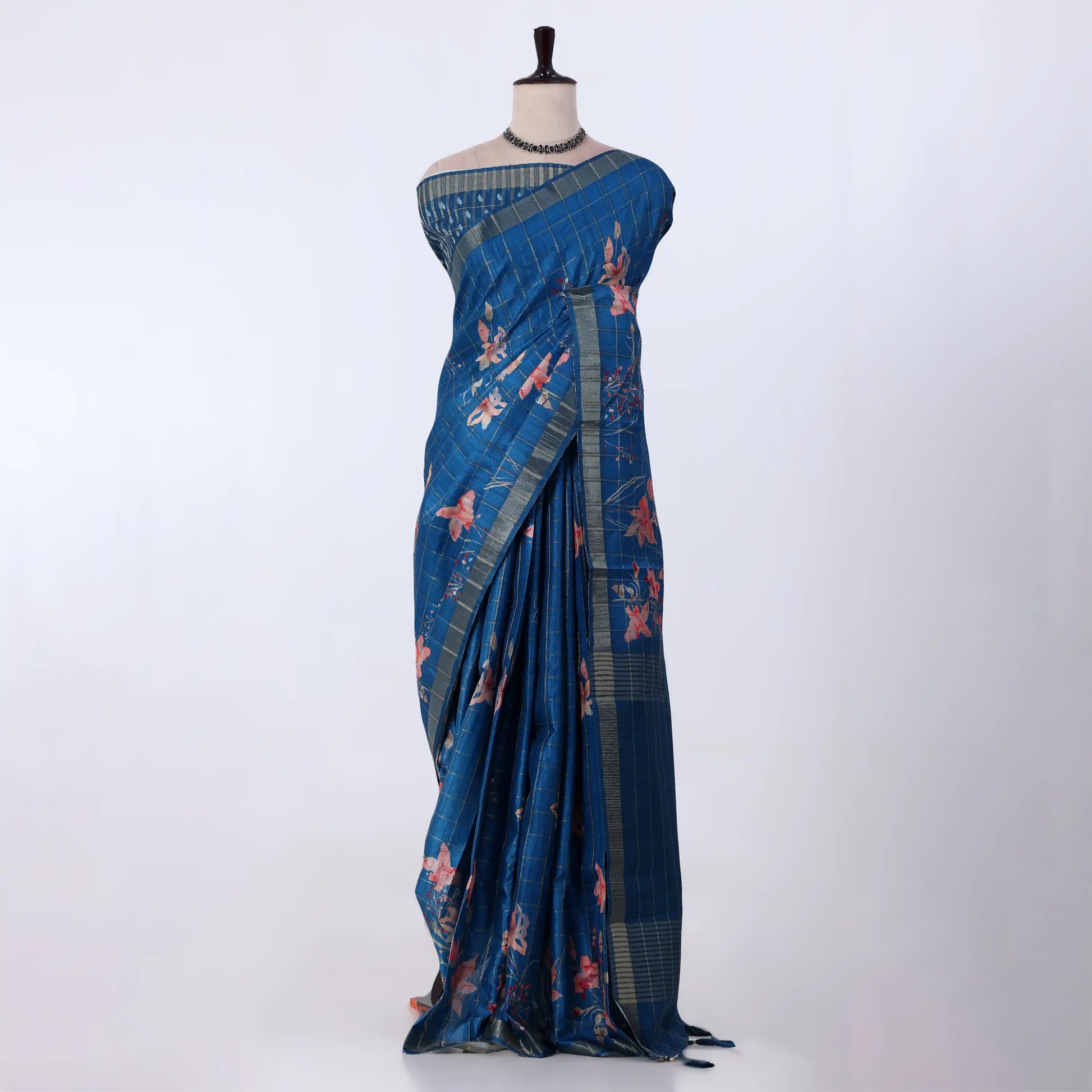 A blue patterned saree with pink floral motifs and striped borders