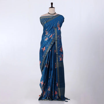 A blue patterned saree with pink floral motifs and striped borders