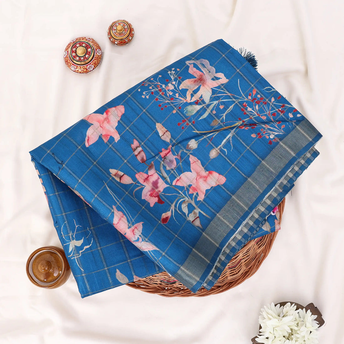 A blue patterned saree with pink floral motifs and striped borders