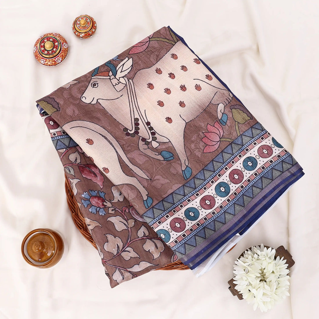 A brown and beige printed saree with blue borders