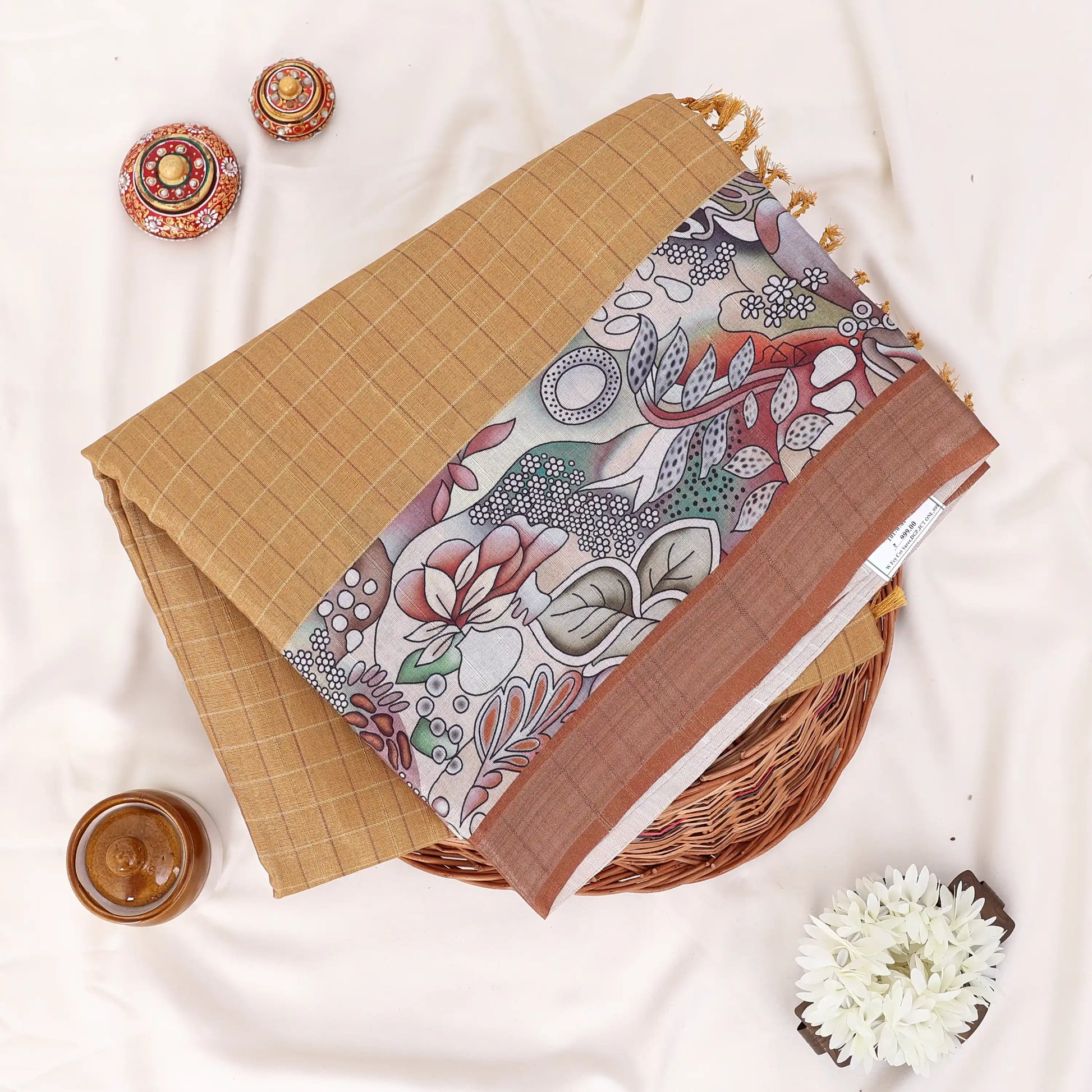 A folded patterned saree with tan grid-patterned section, a dusty rose border, and a central multicolor floral and paisley print