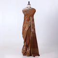 A brown tussar saree with floral prints and a striped border