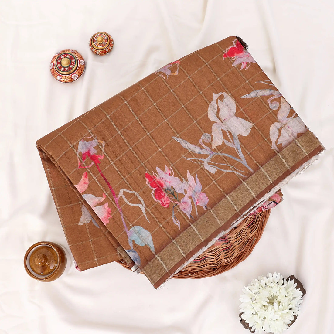 A brown tussar saree with floral prints and a striped border