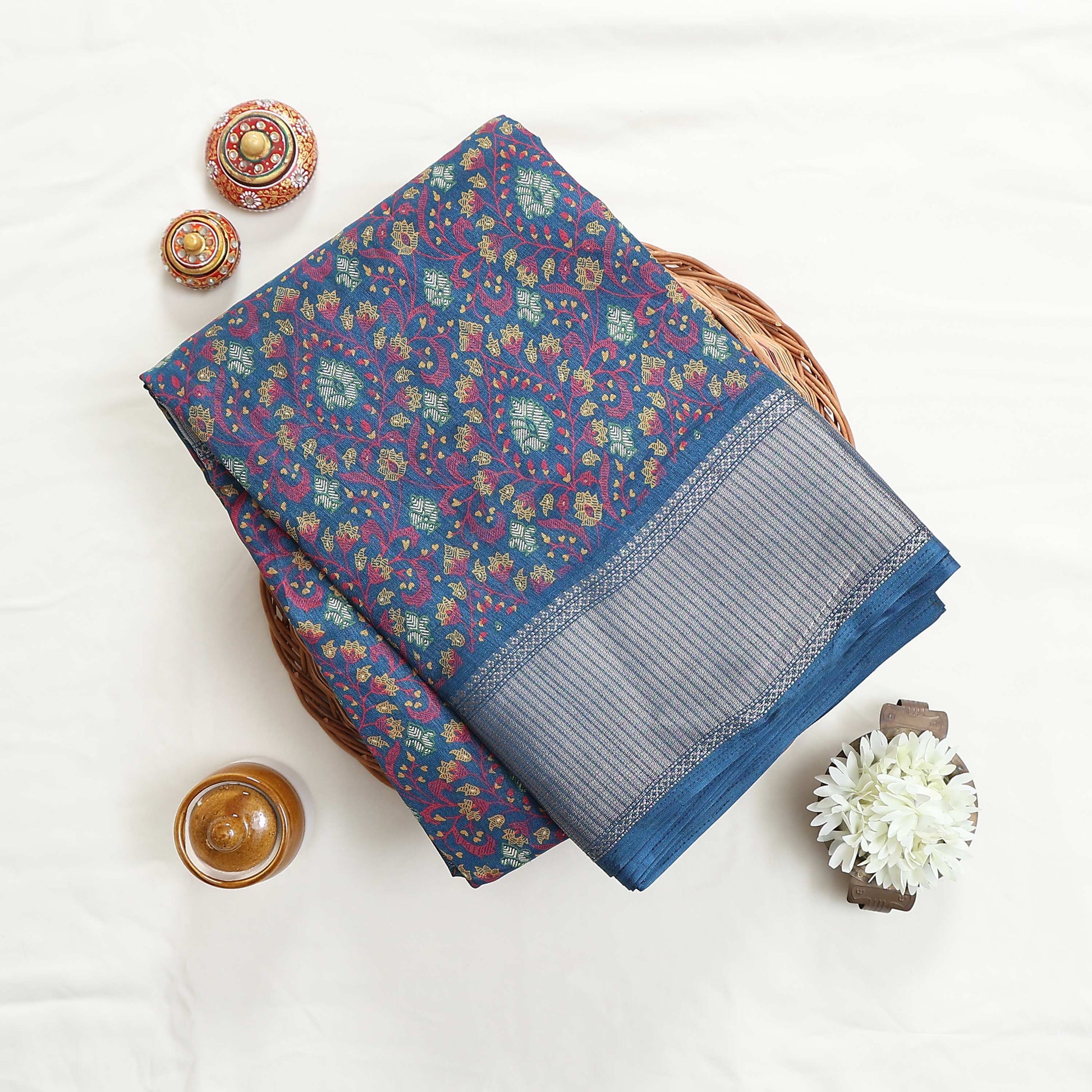 Art silk saree with floral vine jaal pattern and silver zari striped border in blue folded top view display